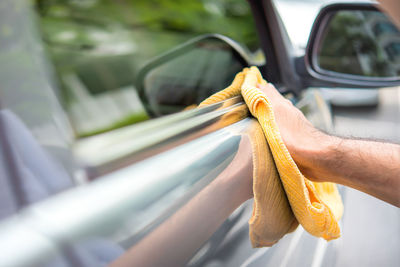 Cropped hand of man cleaning car