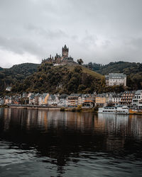 Buildings by river against sky in city