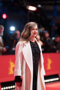 Smiling young woman standing on illuminated at night