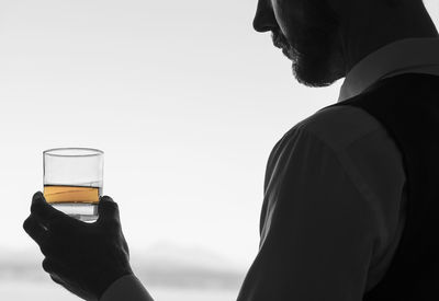 Close-up of man holding drink against sky