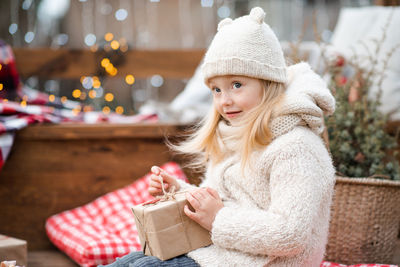 Pretty cute child girl 5-6 year old pack or open christmas present gift over xmas tree outdoor.