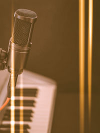 Close-up of microphone with electric piano keyboard in background copy space and light leaks
