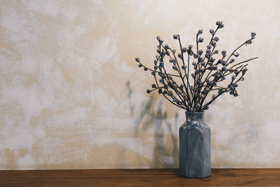 Flower vase on table against wall at home