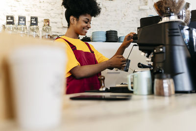 Smiling woman making coffee in cafe