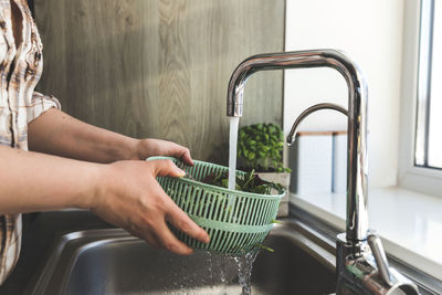 Woman washing green salad leaves for salad in kitchen in sink. high quality photo