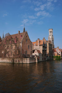 Buildings by river against sky