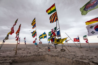 Multi colored flags on beach against sky