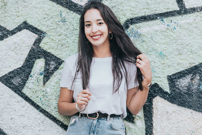 Portrait of young woman standing against wall