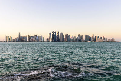 Sea and cityscape against clear sky