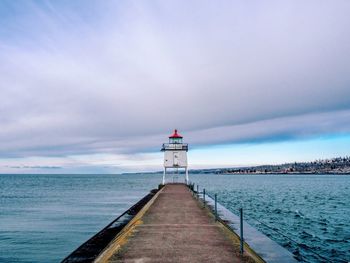 Pier on sea against cloudy sky