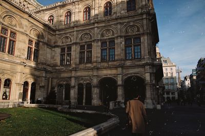 Rear view of woman walking in historic building against sky