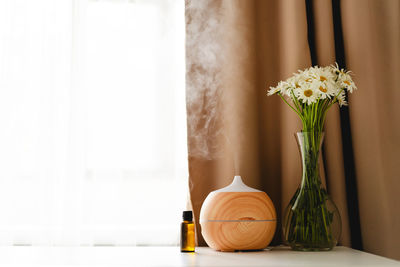 Aromatherapy concept. aroma oil diffuser on the table against the window.