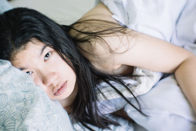 Portrait of young woman lying on bed