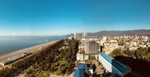 High angle view of townscape by sea against clear blue sky