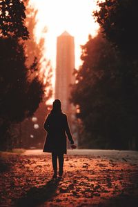 Rear view of silhouette woman walking on street during sunset