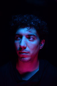 Portrait of young man against black background