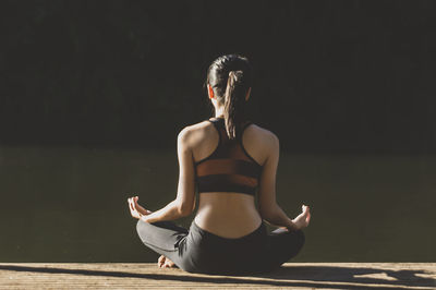 Rear view of woman sitting in lotus position