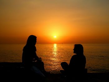 Silhouette of people in sea at sunset