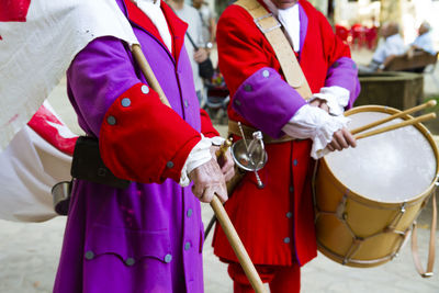 Midsection of people in costume playing drum