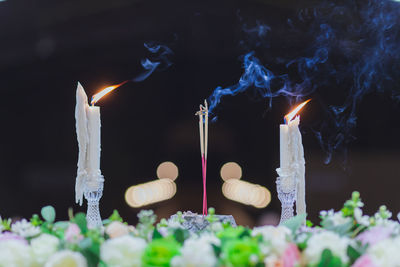 Close-up of lit candles and incense in temple