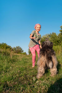 Little girl hugging playing with dog walking spending time together. child with pet in summer meadow