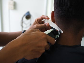 Cropped hands of hairdresser cutting man hair