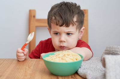 Cute boy is playing with his pasta at lunch time