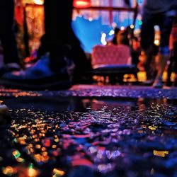 Close-up of wet illuminated street at night