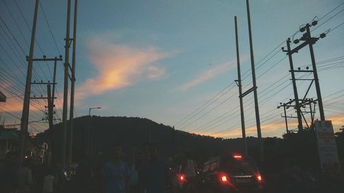 Low angle view of electricity pylon against sky at sunset