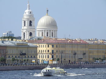 Boats in canal by buildings against sky in city