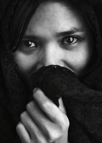 Portrait of young woman covering face with scarf