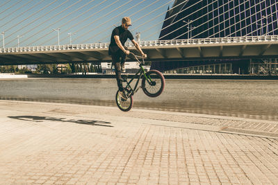 Man riding bicycle on bridge in city