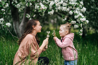 Mother and daughter with dandelions blooming apple trees