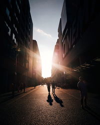 Silhouette people walking on street in city during sunset