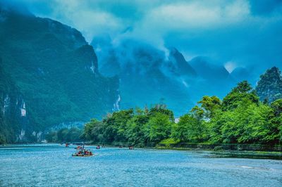 Scenic view of lake by mountains against cloudy sky