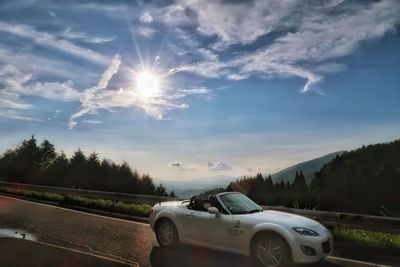 Car on road against sky at sunset