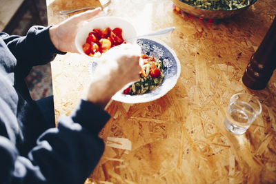 Midsection of man eating cherry tomatoes and pasta at home