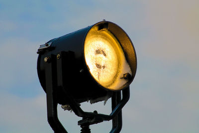 Low angle view of illuminated spotlight against sky