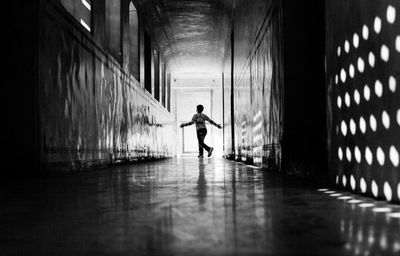 Boy running in corridor on sunny day