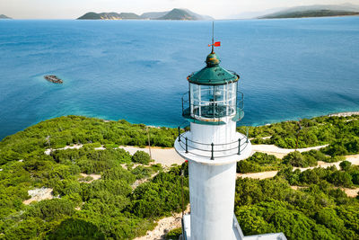 Lighthouse by sea against sky