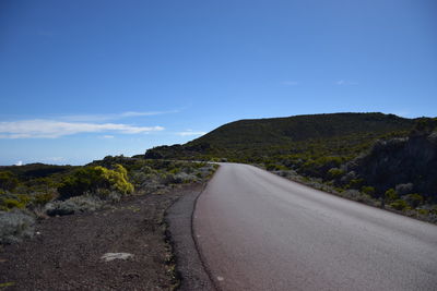 Road by mountain against blue sky