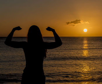 Silhouette woman standing by sea against sky during sunset