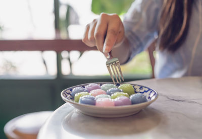 Midsection of woman holding ice cream in bowl on table