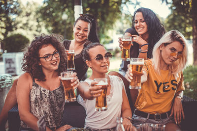 Portrait of smiling women showing beer glasses at party