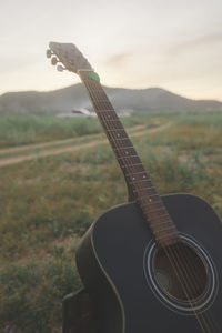 Close-up of guitar on field against sky