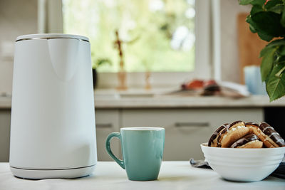 Electric kettle and cup for tea on table