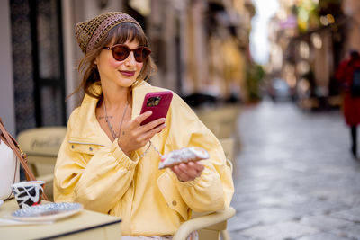 Young woman using mobile phone while sitting on chair