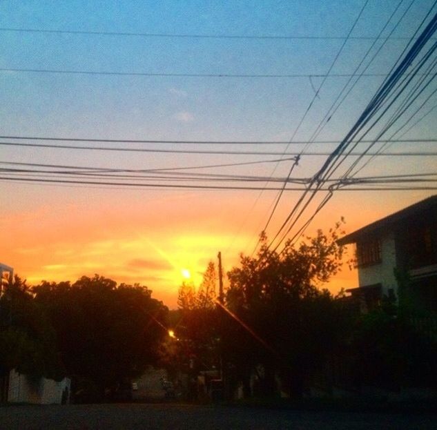 sunset, power line, building exterior, electricity pylon, tree, built structure, sky, architecture, silhouette, orange color, cable, electricity, power supply, house, sun, power cable, sunlight, city, cloud - sky, connection