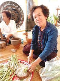 Portrait of mature woman chopping spring onions on floor