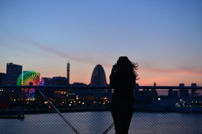 Silhouette woman standing by railing at minato mirai against sky